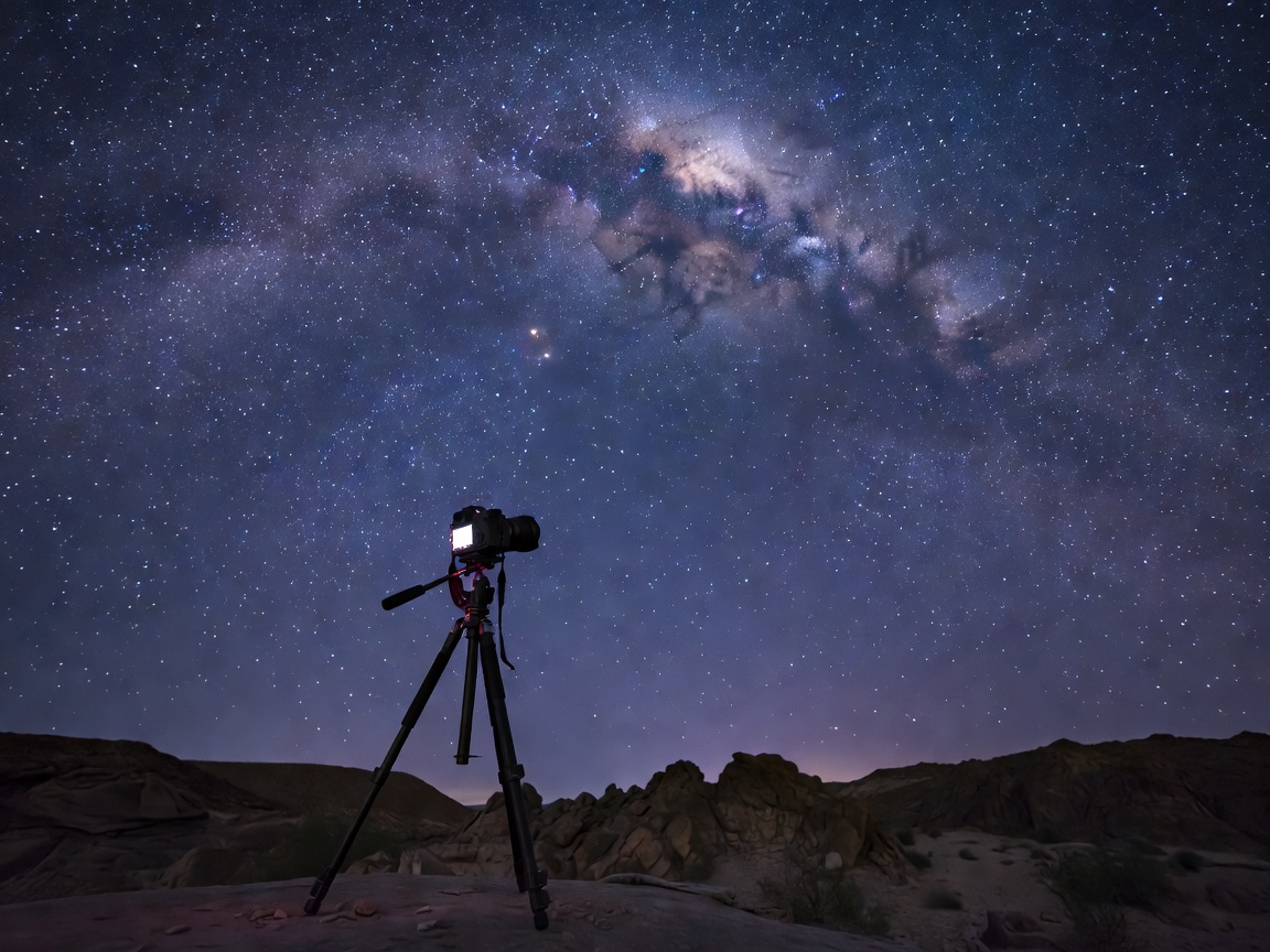 Camera on a tripod capturing a long exposure of the night sky