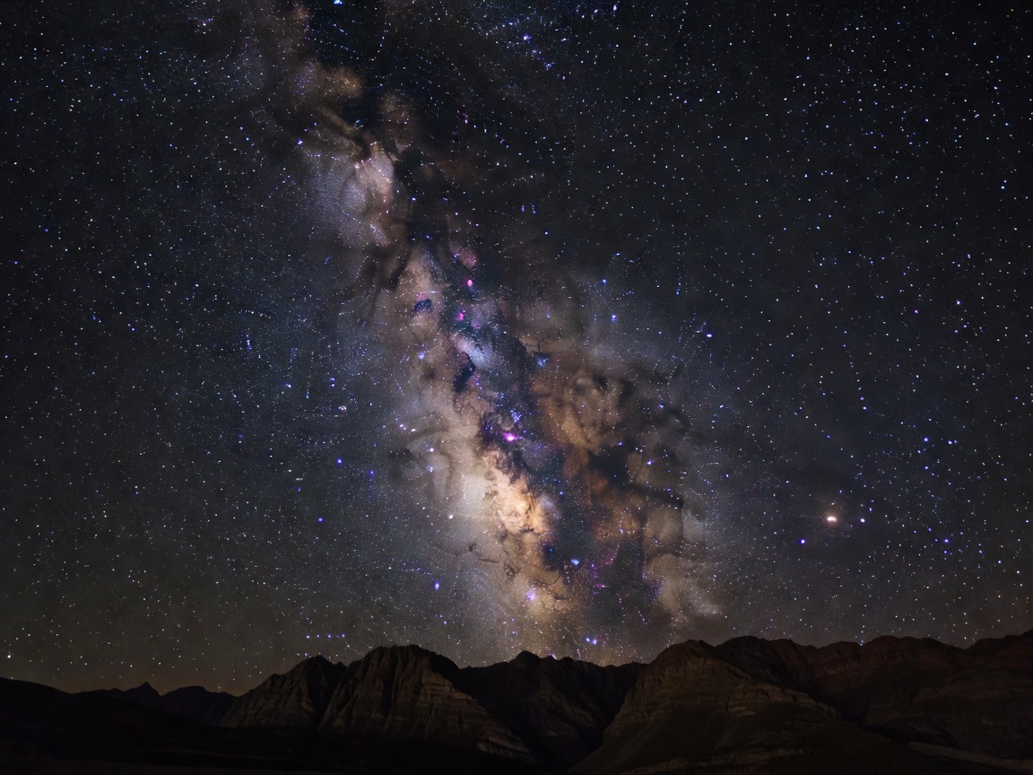Milky way visible over a dark mountainous horizon